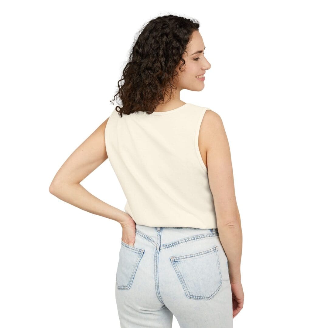 Woman wearing a sleeveless light beige top and light blue jeans, viewed from the back.