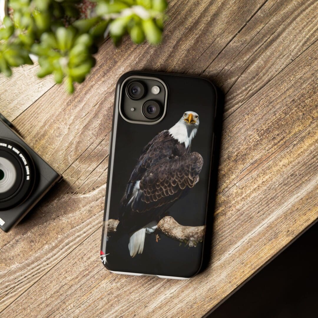 Phone case featuring a bald eagle design on a wooden surface.