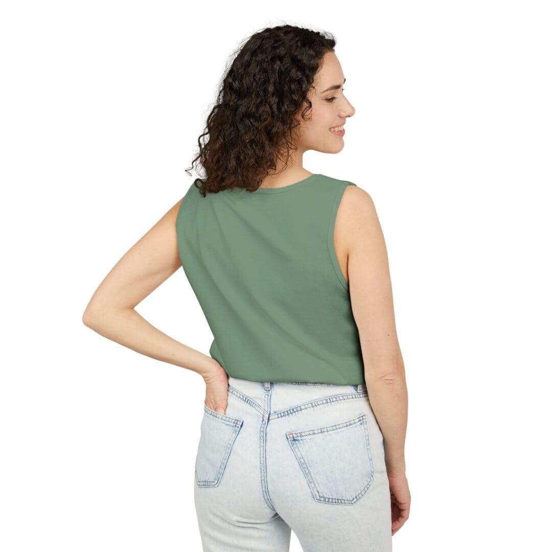Woman in green sleeveless top and light denim jeans, facing away.