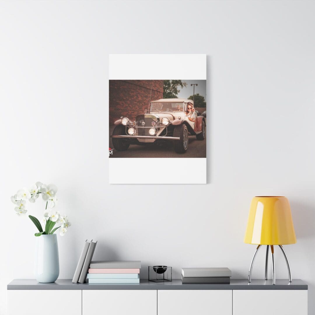 Vintage car photograph hanging above a modern white desk setup.
