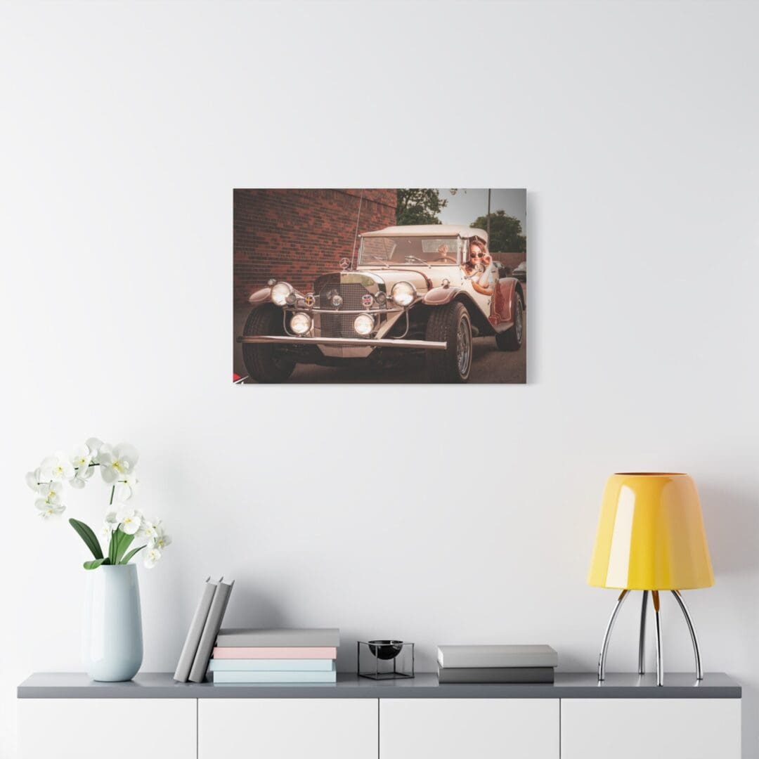 Vintage car photograph hanging above a modern white shelf with decor.