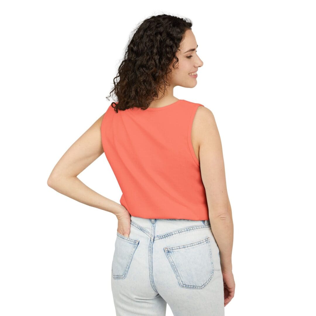 Woman in orange sleeveless top and light denim jeans posing with back turned.