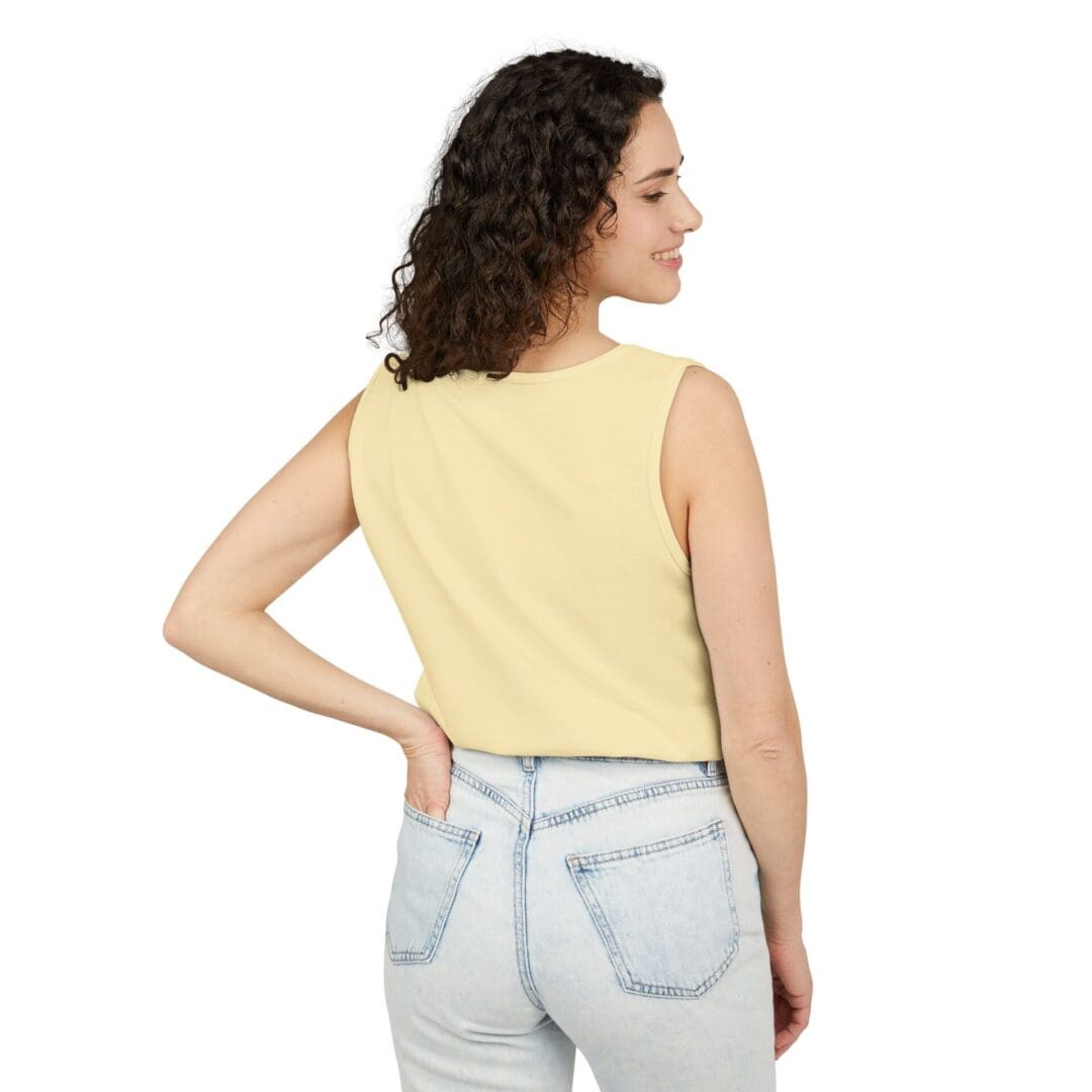 Woman in a yellow sleeveless top and light jeans, facing away.