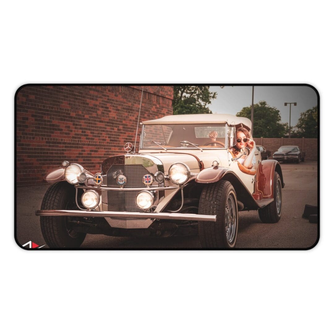 A vintage car parked on a street with a brick wall background.
