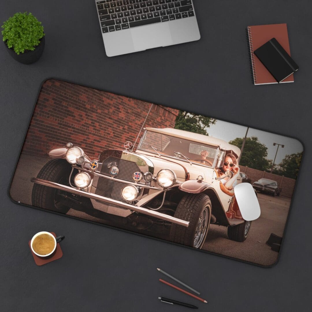 A vintage car with a person sitting beside it on a large desk mat.
