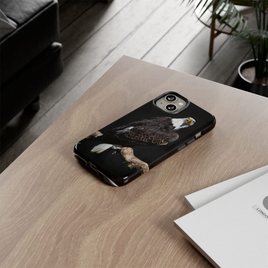 Black phone case with a white and tan skull design on a wooden table.