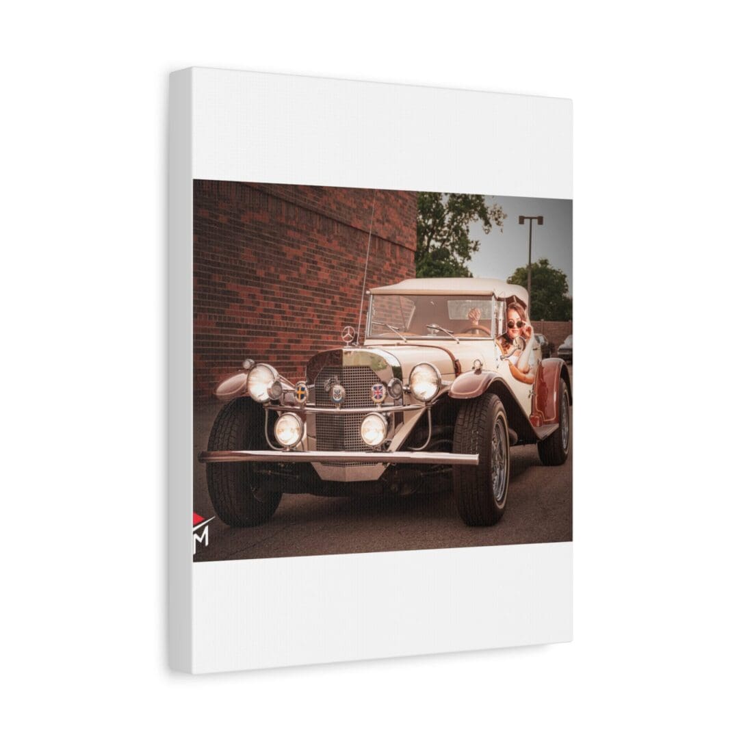 A vintage car parked against a brick wall with some greenery above.