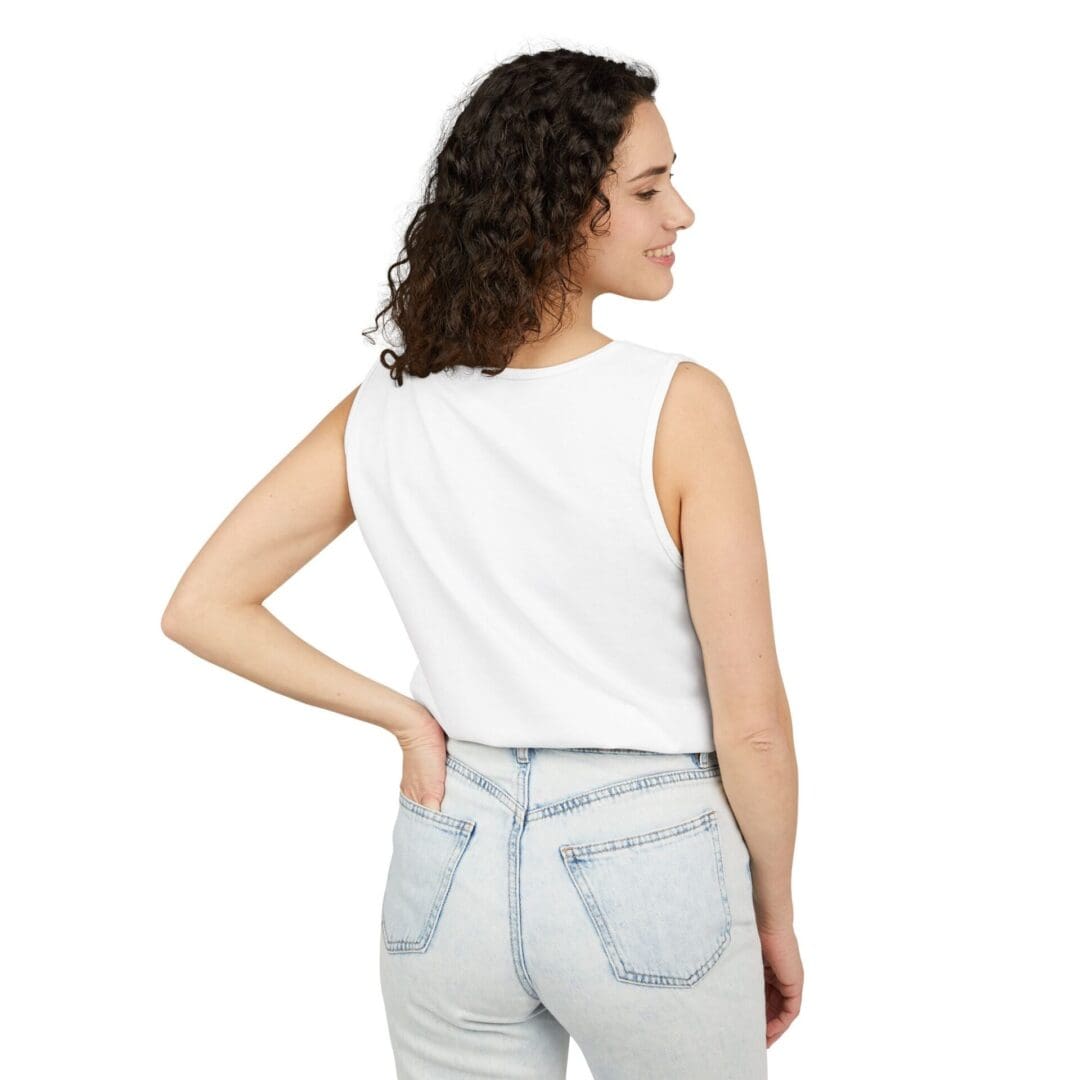Woman with curly hair wearing a white sleeveless top and light blue jeans, posing with her back to the camera.