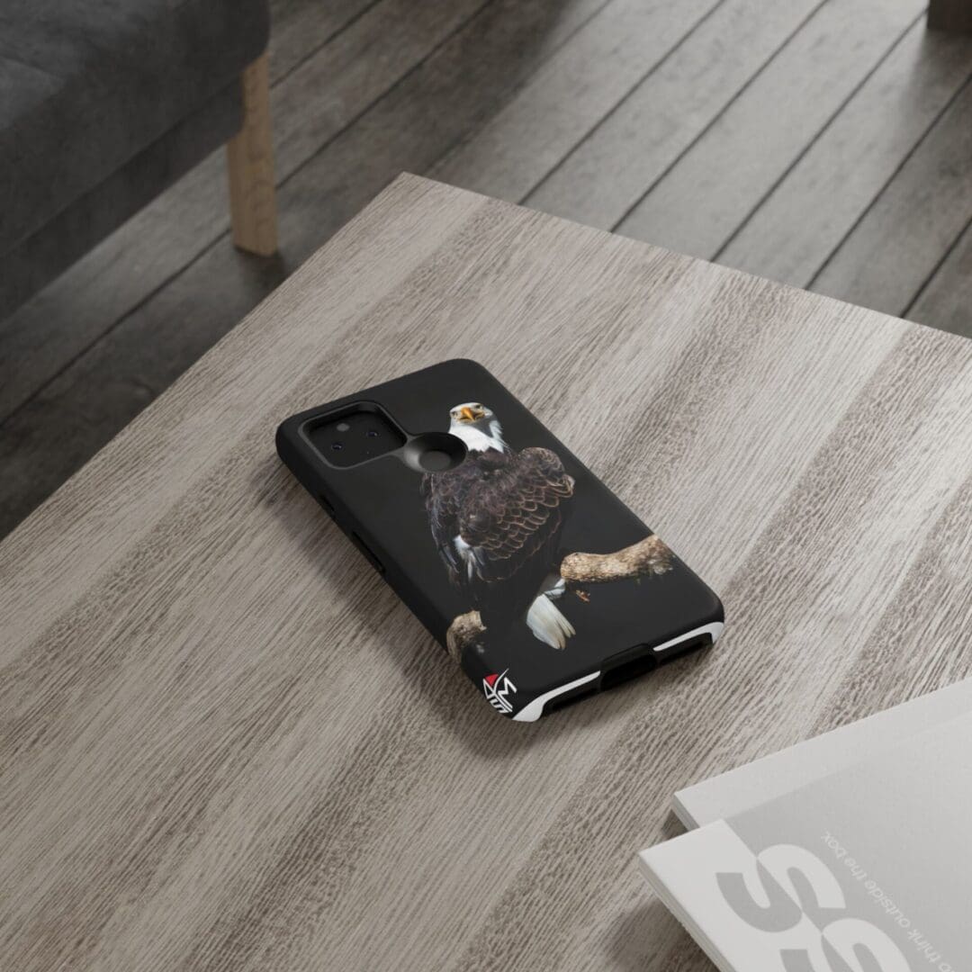 Smartphone with a black case resting on a wooden table.
