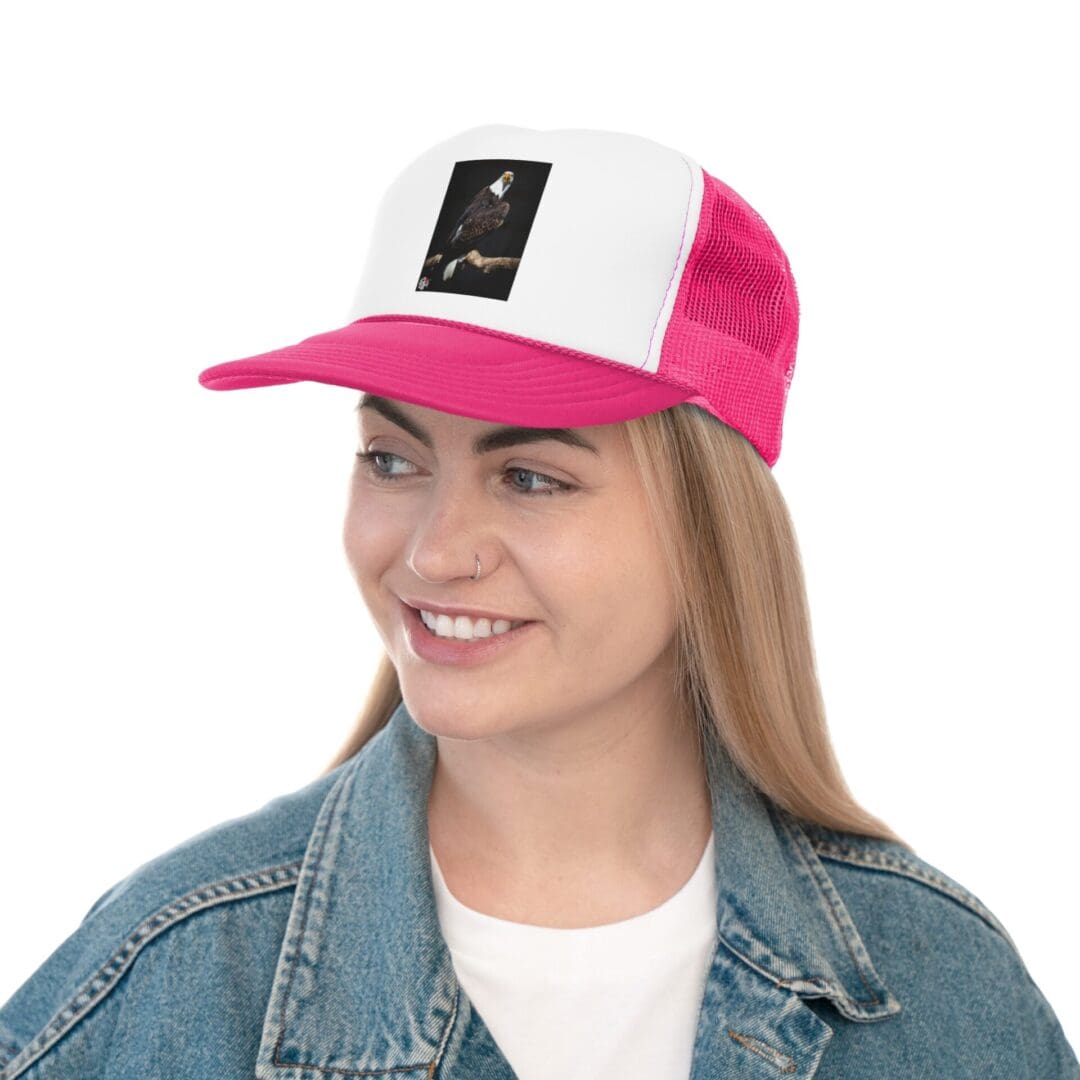 A young woman wearing a pink and white baseball cap and denim jacket, smiling.