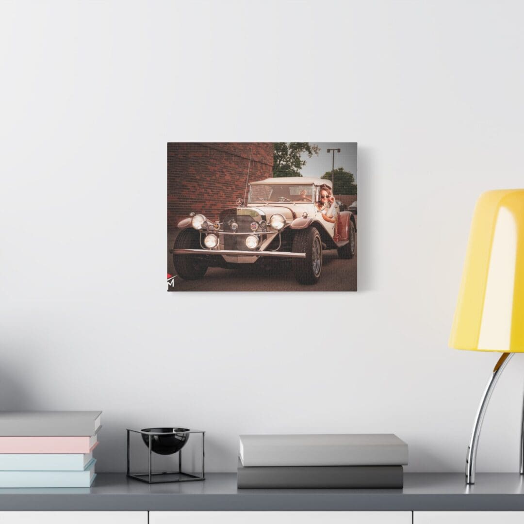 Vintage car painting hanging on a white wall above a modern desk setup.