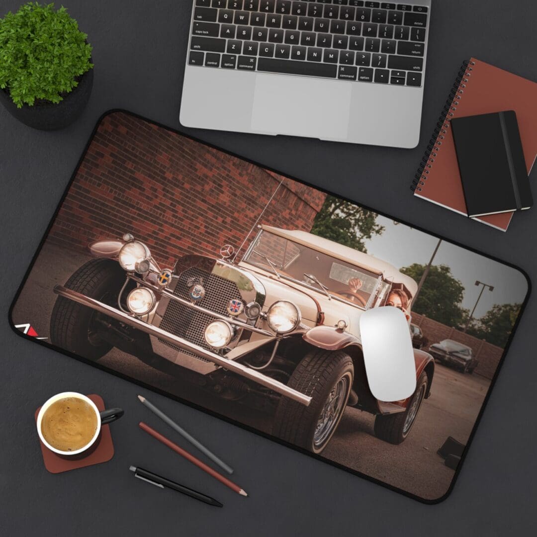 Desk setup with a vintage car-themed mouse pad, laptop, coffee, and stationery.