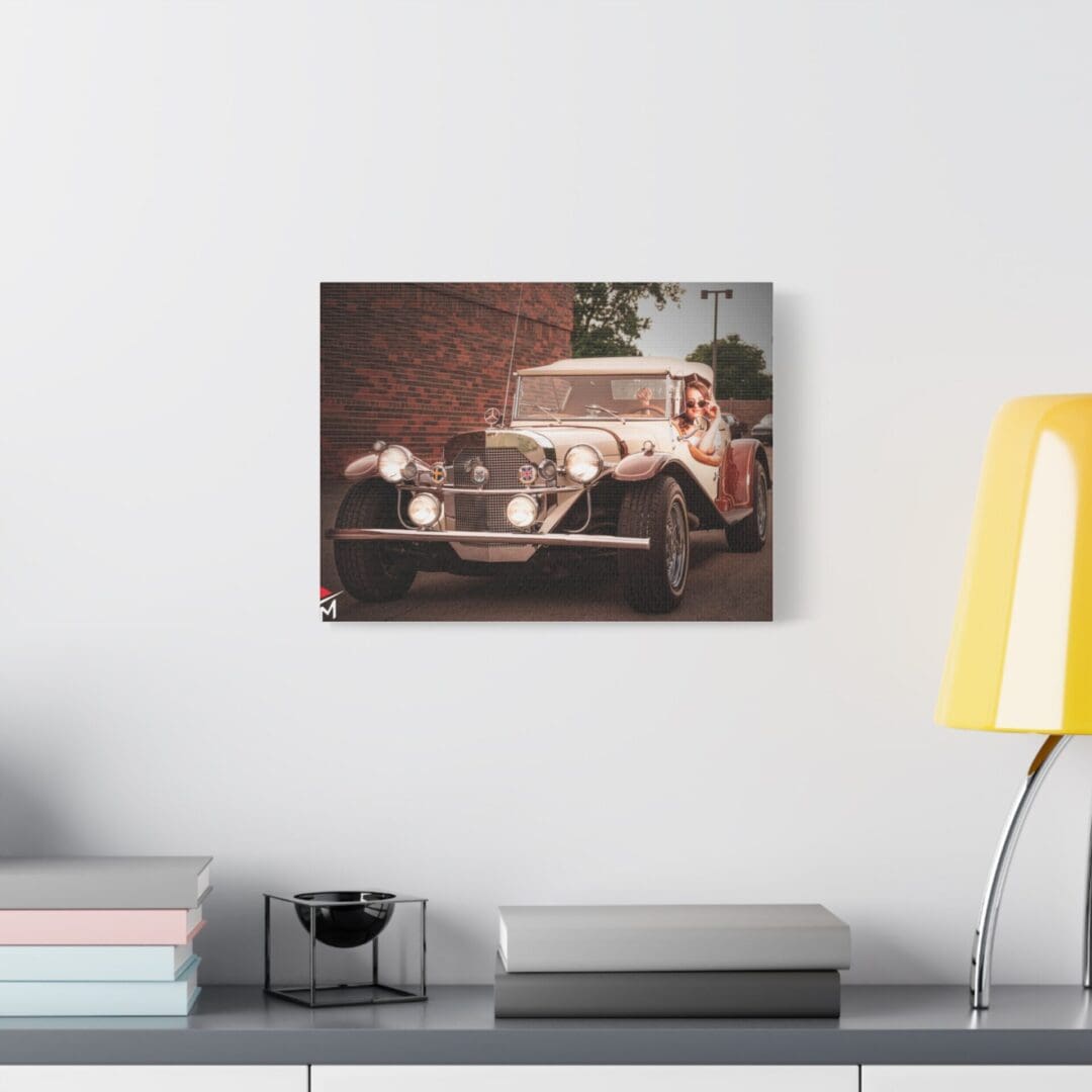 Vintage car photo hung above a modern white desk setup.