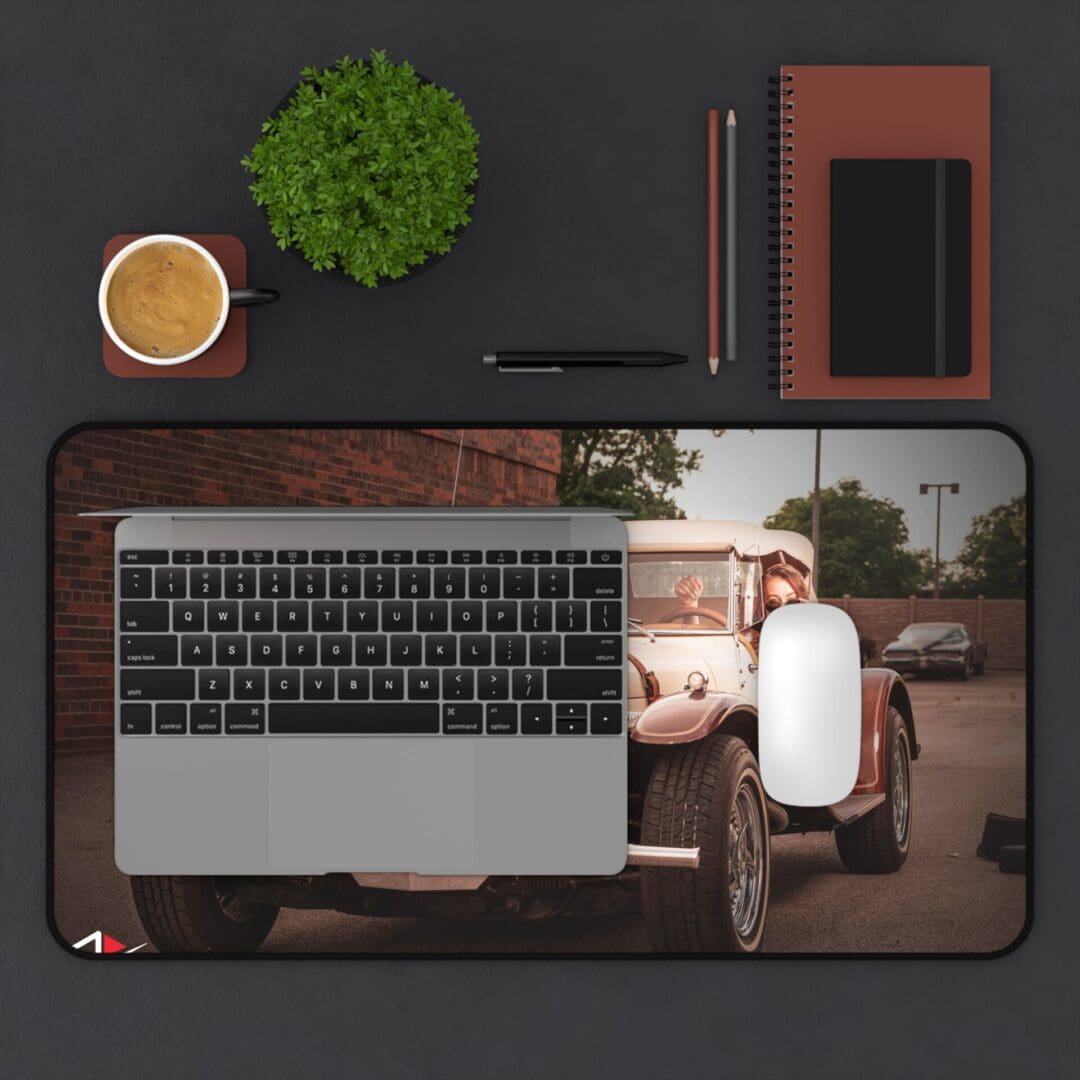 A workspace with a laptop, mouse, notebook, coffee, and plant on a desk mat.