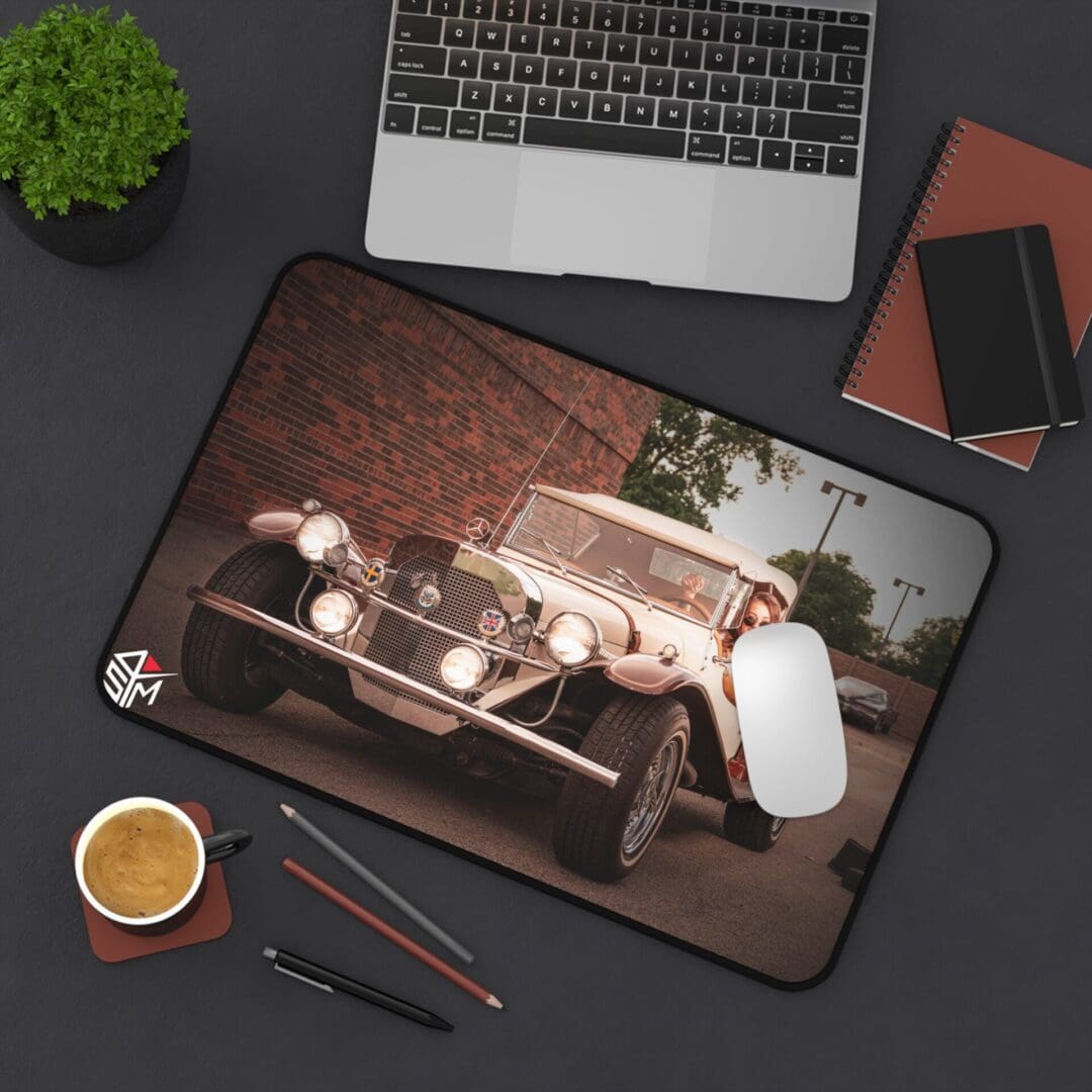 Laptop and accessories on a dark desk with a vintage car mouse pad.