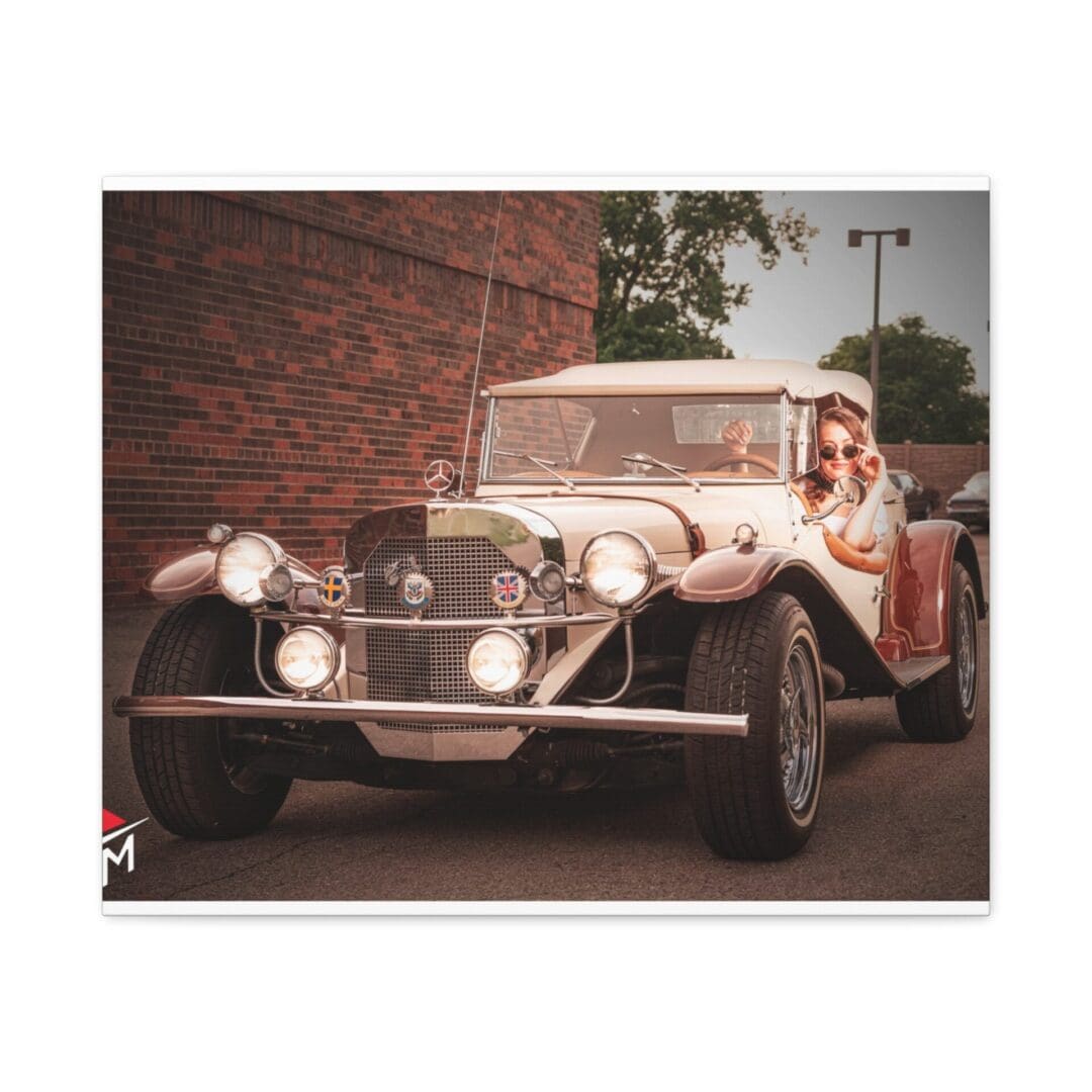 Vintage convertible car parked near a brick wall with a person inside.