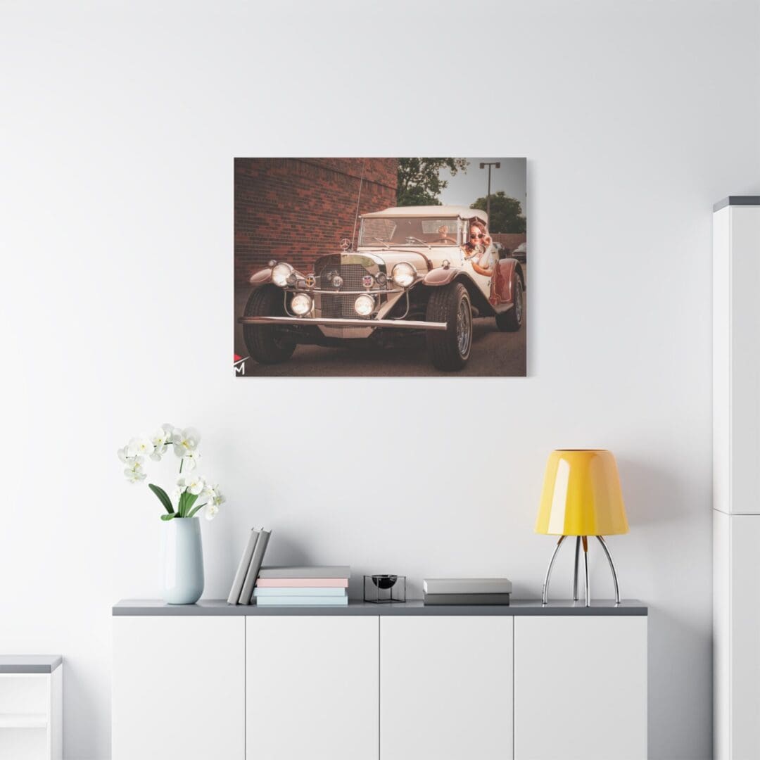 Vintage car photo hanging above a modern sideboard with decor.