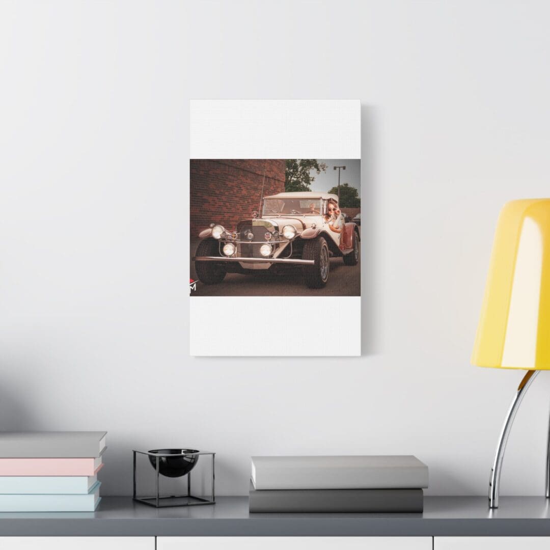 A cozy wall calendar with a vintage car photo hangs above a desk with a yellow lamp.