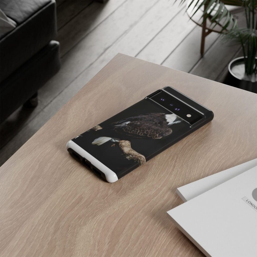 A black phone case with a white cat design on a wooden table.