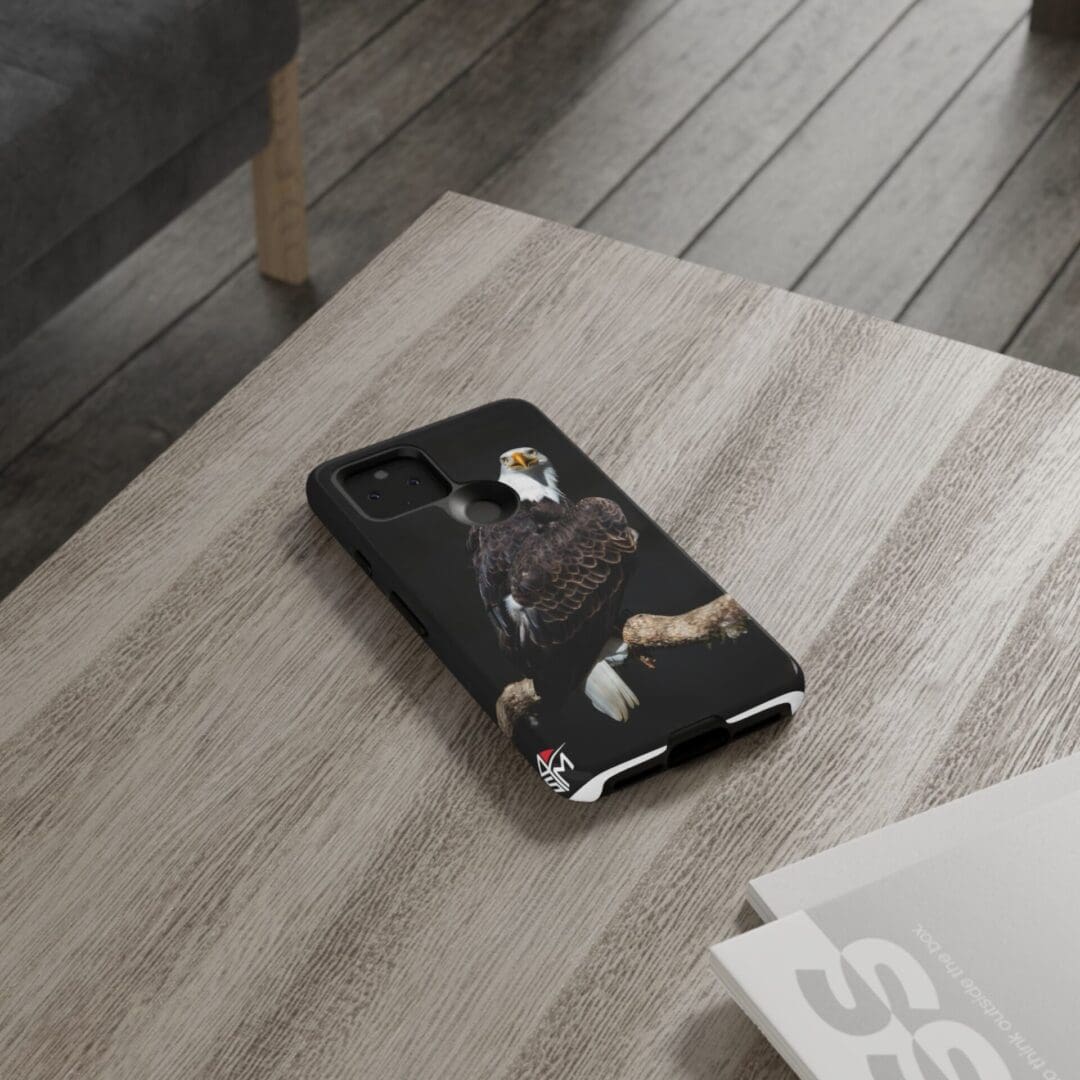 Phone with a black-and-white cat case on a wooden table.