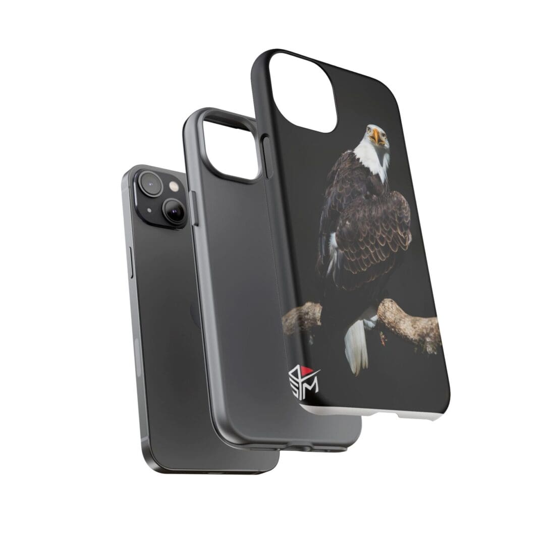 Two black phone cases and a phone, one case featuring a cat design.