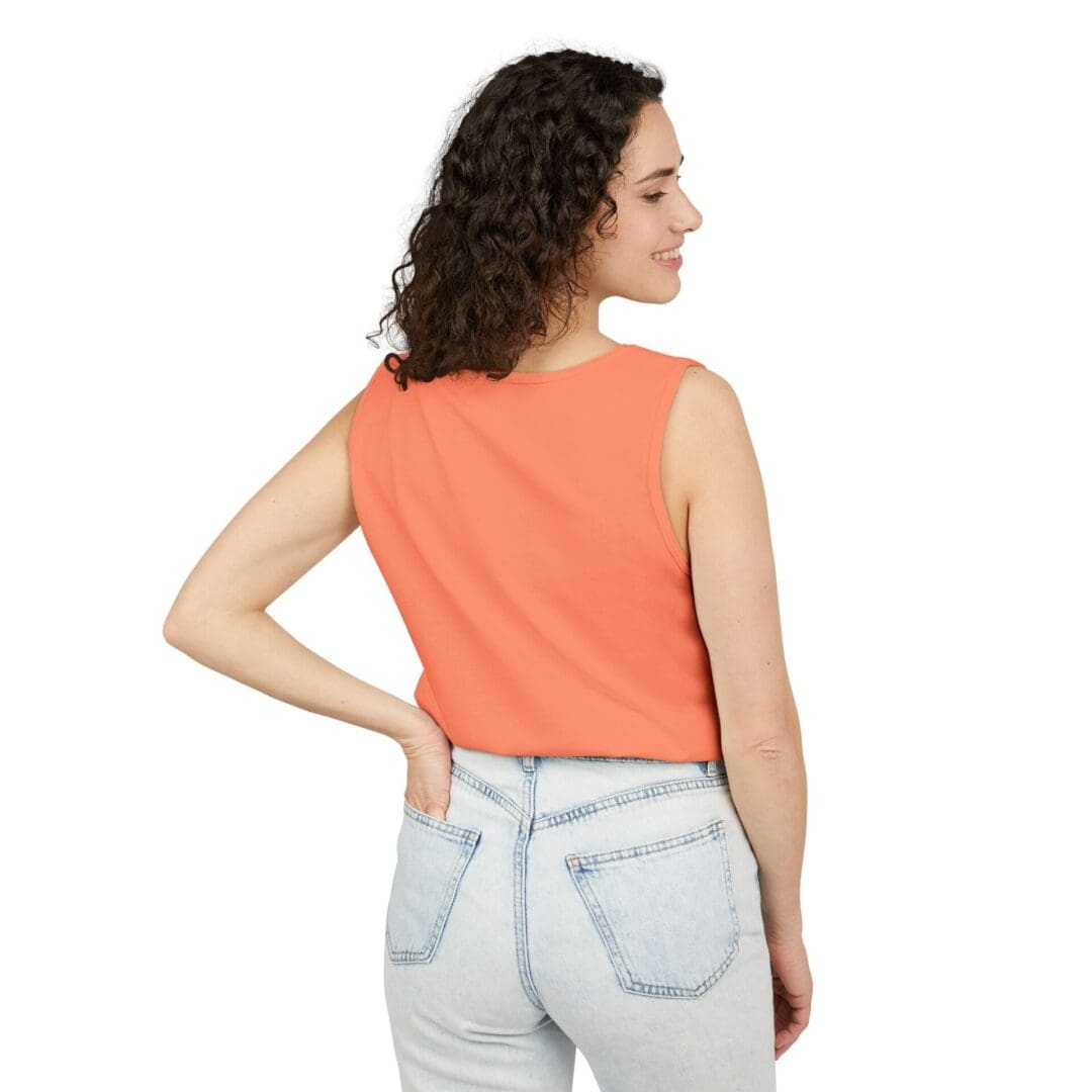 Woman in an orange sleeveless top and light blue jeans, facing away.